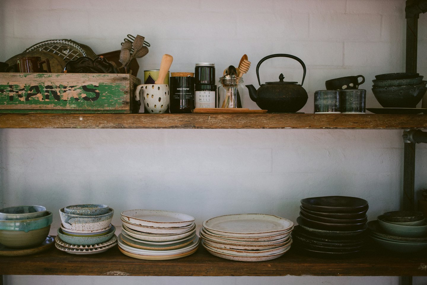 Stoviglie e utensili da cucina in ceramica fatti a mano su mensole in legno rustico.