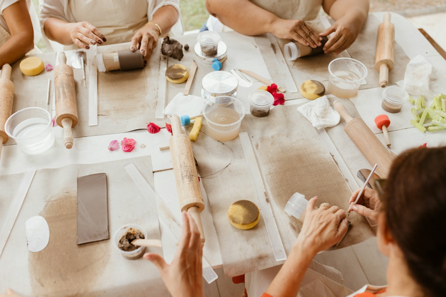 Mani che lavorano a progetti di ceramica su un tavolo da laboratorio.
