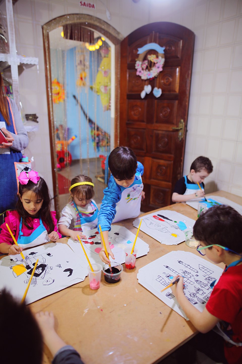 Bambini impegnati in un'attività artistica creativa a un tavolo di legno.
