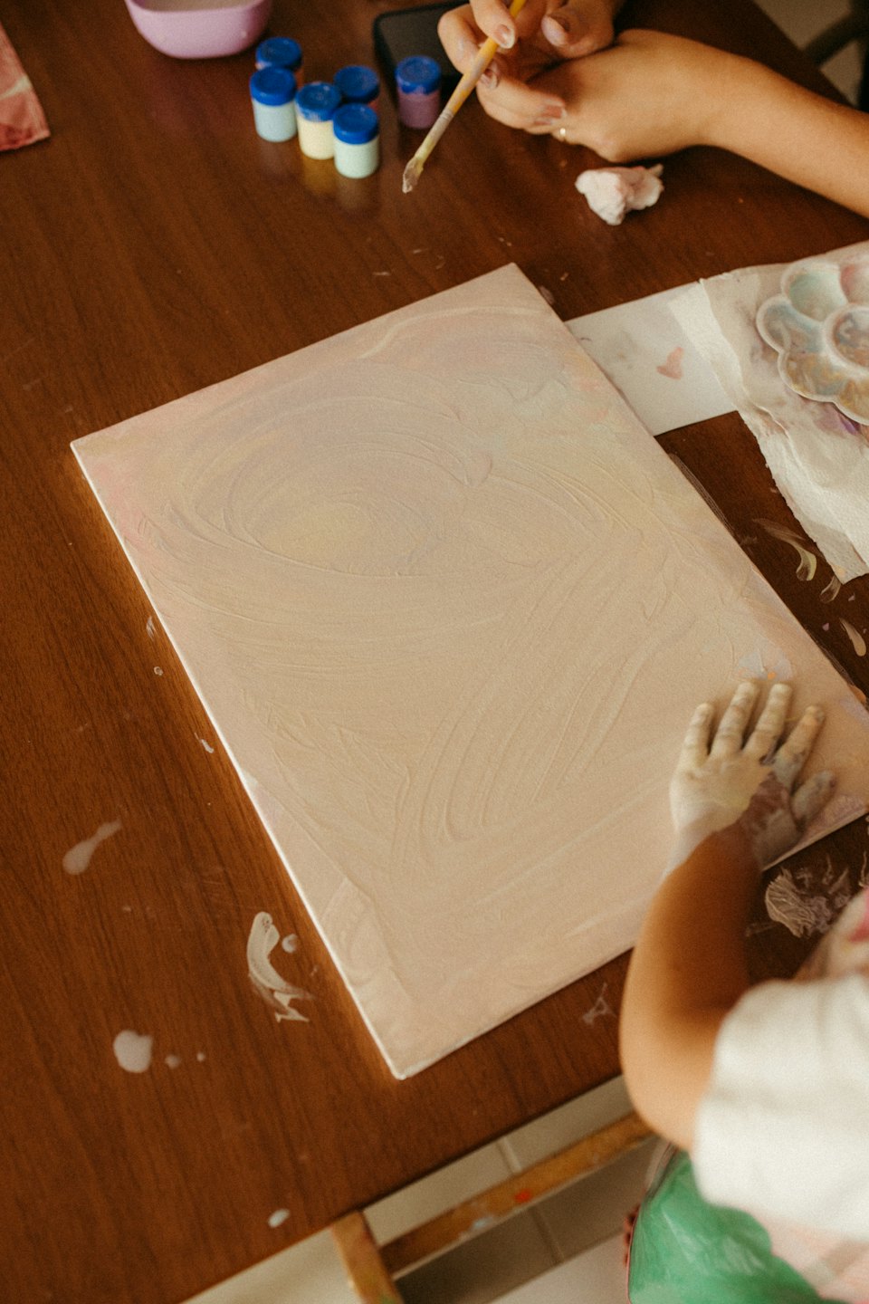 Adulto e bambino dipingono insieme con materiale artistico sparso.